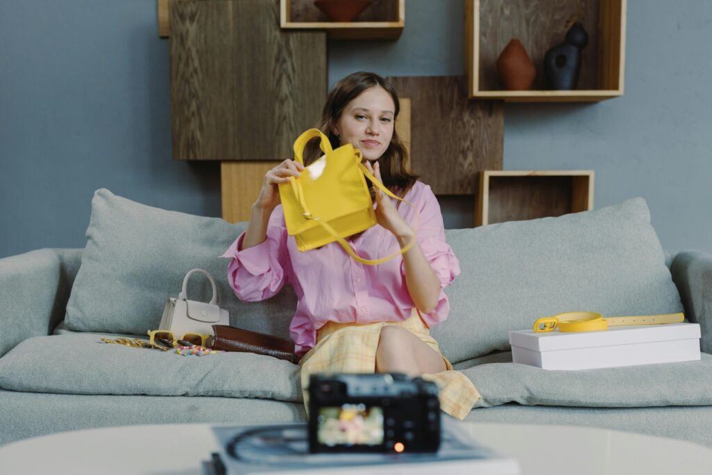 A young woman showcasing a yellow handbag during a live online fashion sale session.